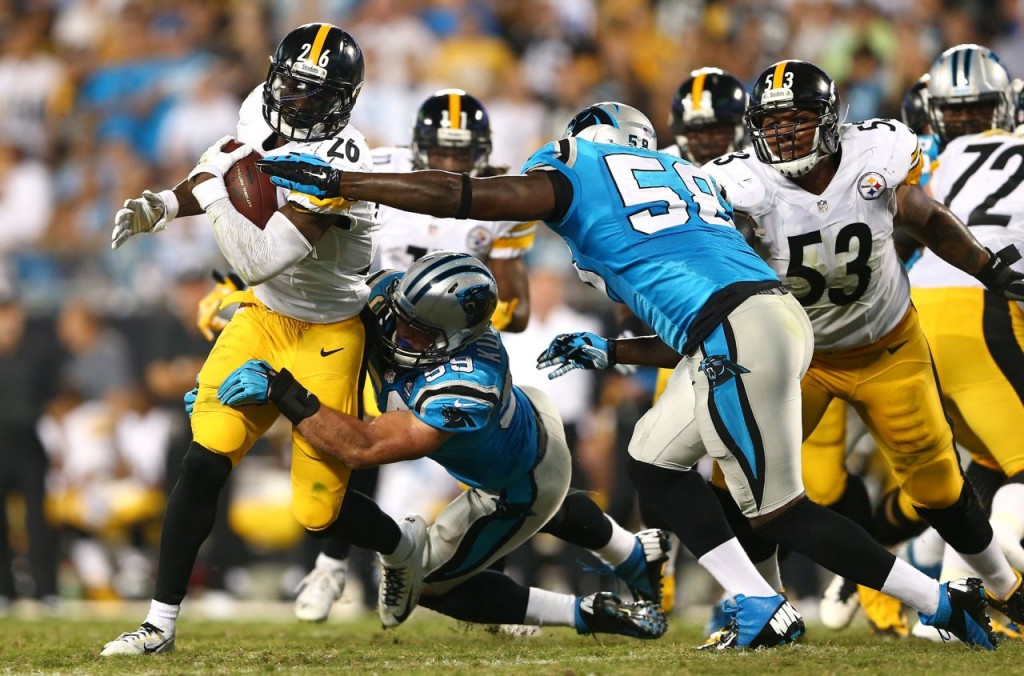 Le'Veon Bell bursts through the offensive line and around Carolina's Luke Kuechly Sunday night. -- GETTY IMAGES